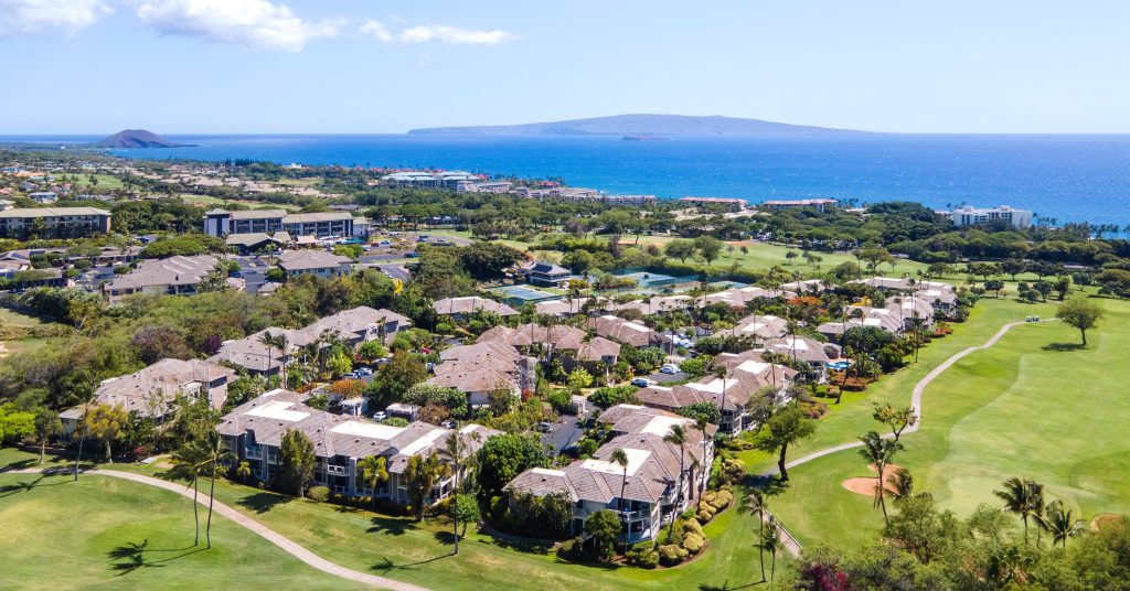 Aerial view of Grand Champions Villas in Wailea, Maui, showcasing lush golf course, tropical landscaping, and sweeping ocean views.