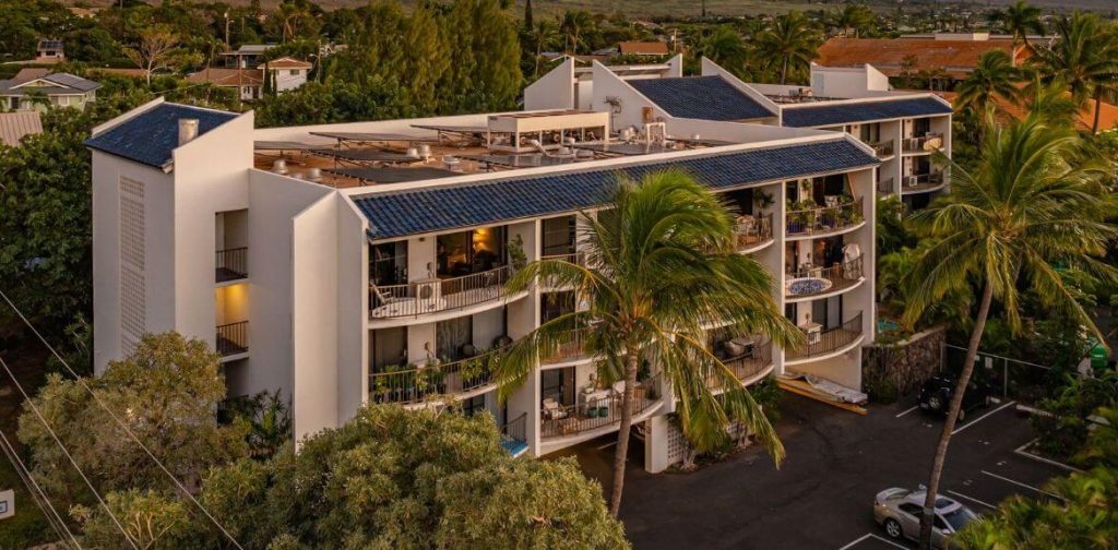 Exterior view of Kamoa Views condo building in South Kihei, Maui, showing boutique architecture, rooftop solar panels, private lanais, and surrounding neighborhood