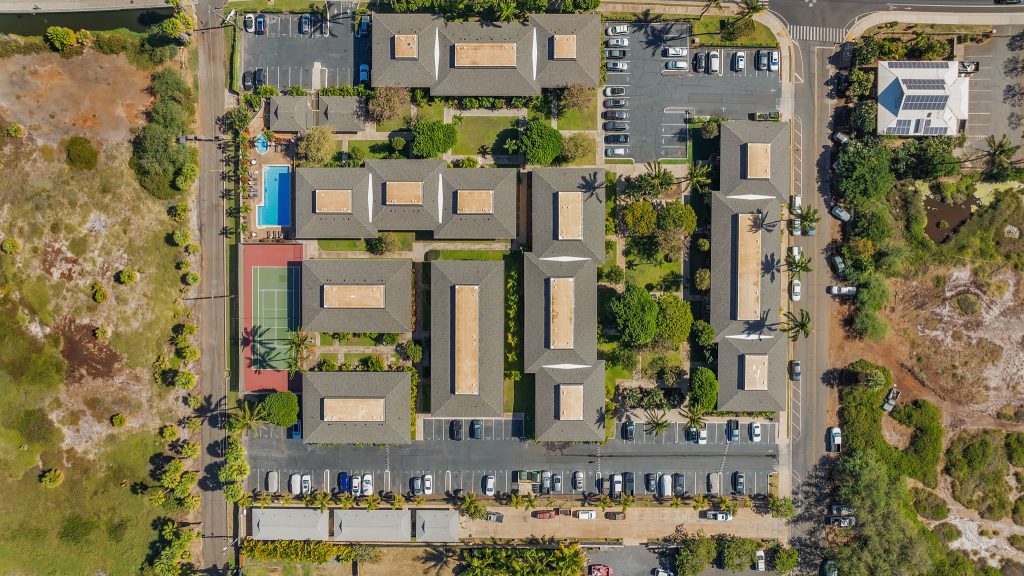Aerial view of Maui Gardens condo complex in Kihei, Maui, showing building layout, swimming pool, hot tub, tennis court, landscaped grounds, and parking areas