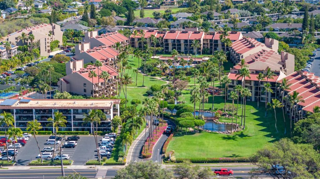 Aerial view of Kamaole Sands condo complex in South Kihei, Maui with tropical landscaping, red rooftops, and a central pool area near Kamaole Beach Park III