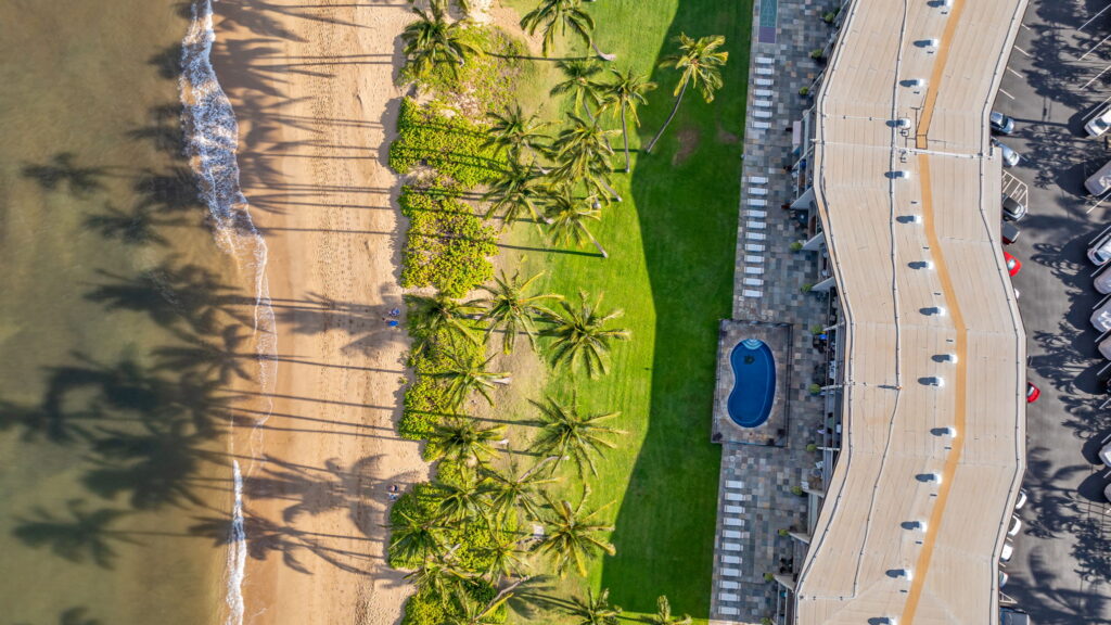 Top-down aerial view of Hale Kai O Kihei beachfront condos, oceanfront lawn, and Lipoa Street Beach in South Kihei, Maui